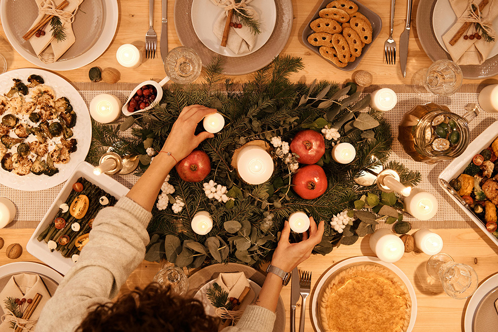 Mesa navideña sostenible decorada con velas, hojas secas y vajilla reutilizable para unas fiestas ecológicas