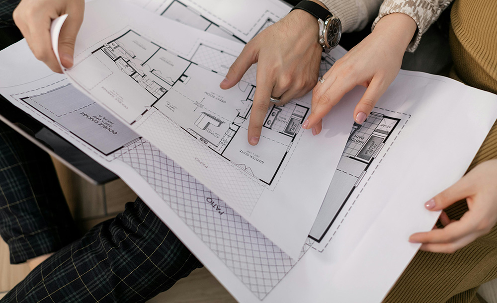 Pareja noven revisando planos de su futura vivienda